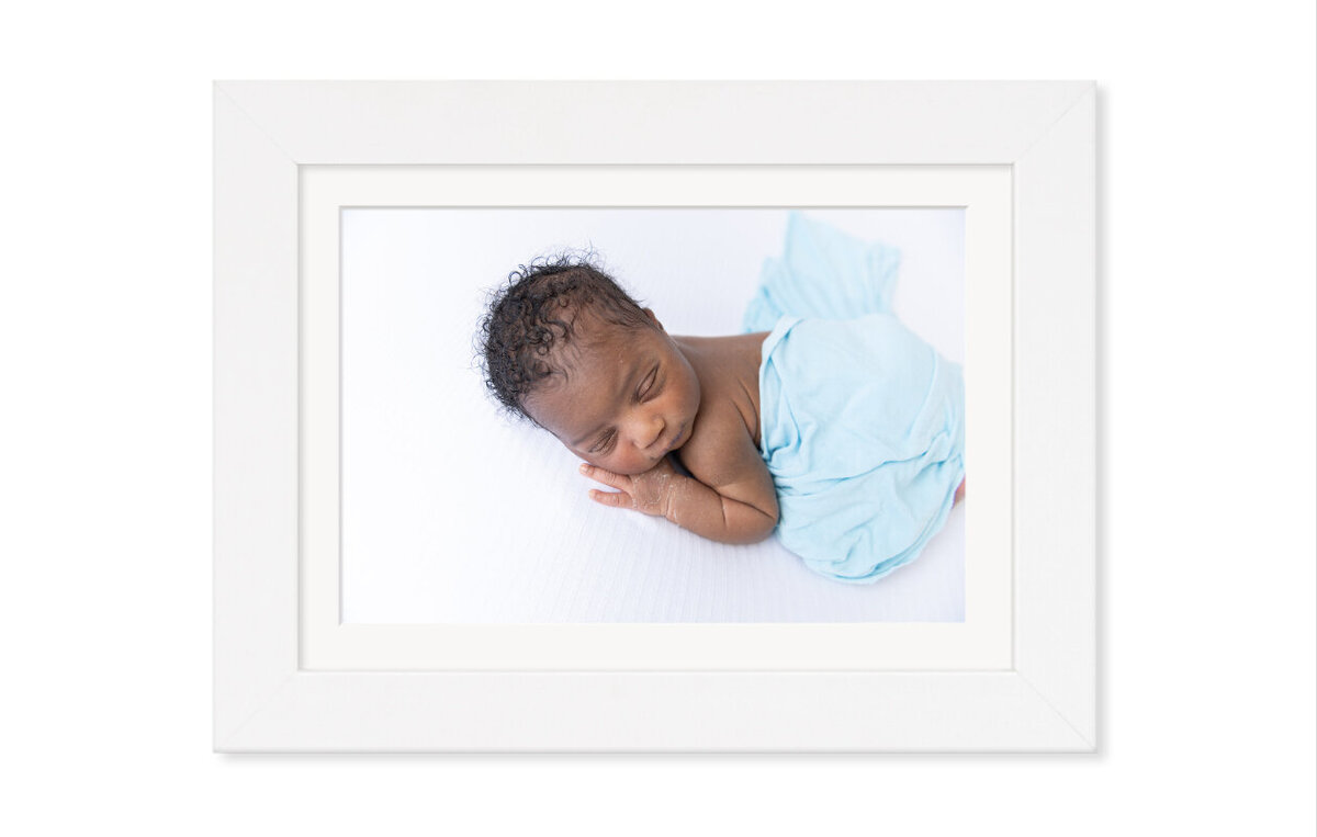 A sleeping newborn baby photograph framed on a wall