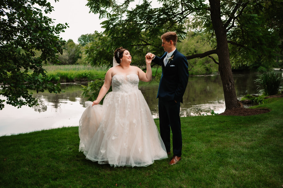 Newlyweds dance in a lawn by a pond