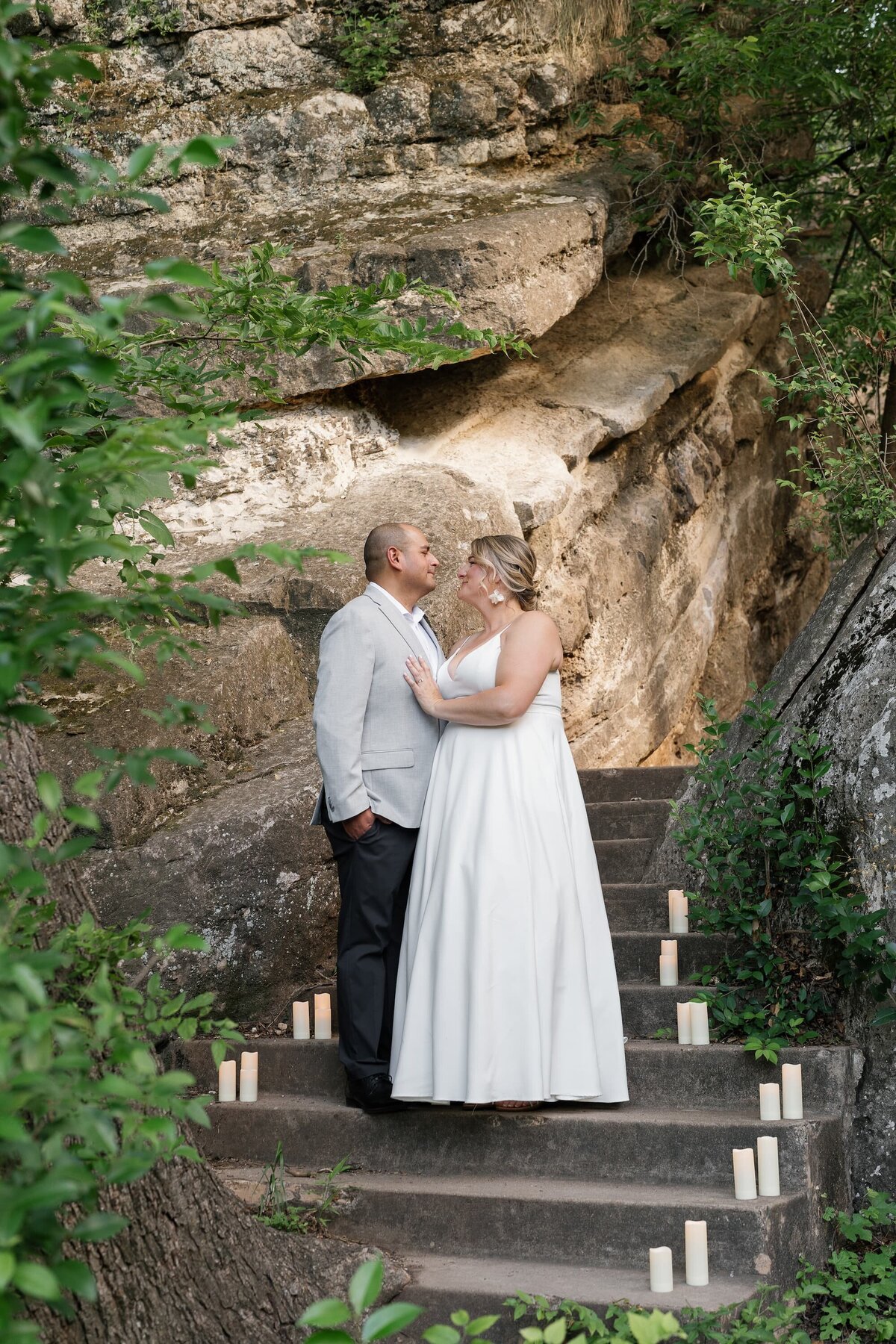 Jen and Miguel on stone steps during their Austin elopement surrounded by candles