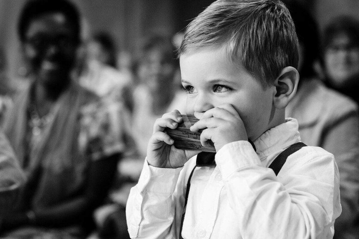 Timeless black and white photo of a young ring bearer capturing a heartfelt moment during a wedding ceremony. A candid portrayal of childhood charm and celebration.