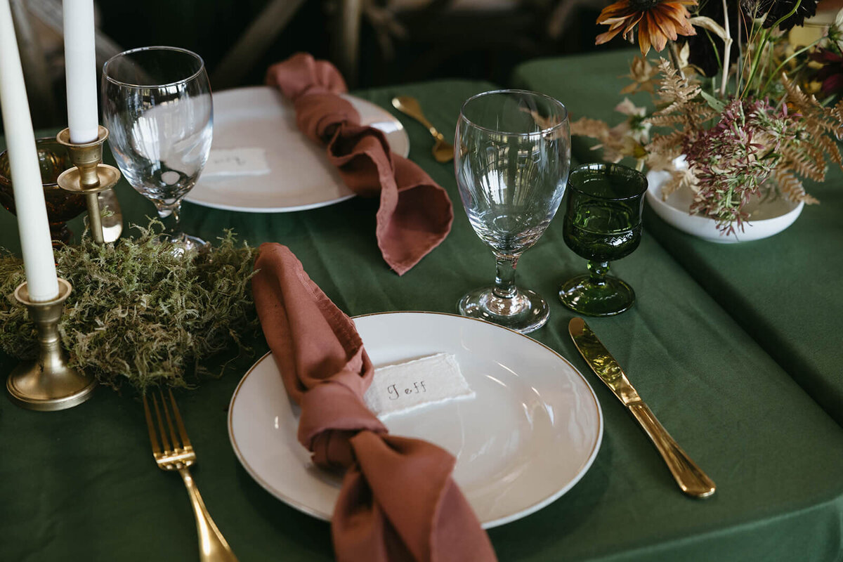 A wedding table setting including cloth napkins, tableware and flowers.
