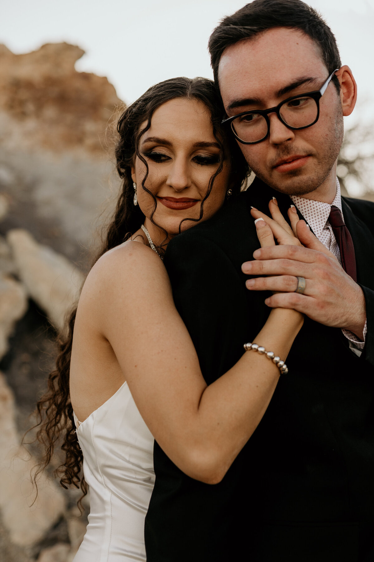 bride hugging groom from behind in the desert