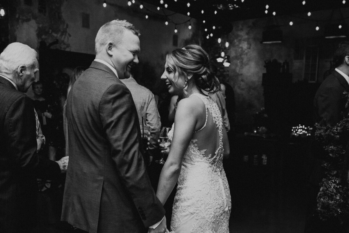 Bride and groom holding hands and looking at each other smiling on the dance floor at their wedding