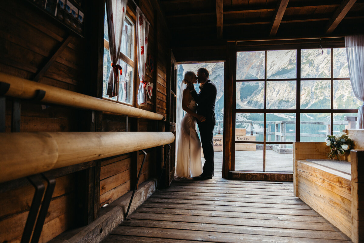 Bride and groom silhouette inside rustic boathouse window