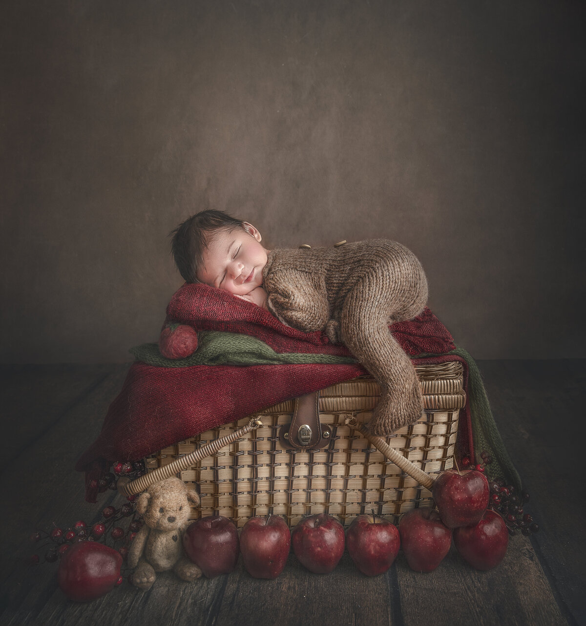 baby sleeping in a basket surrounded by apples during his  newborn photography session in the studio in Ottawa Ontario