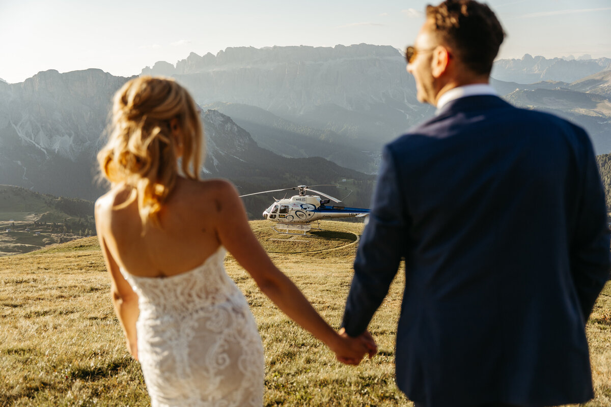 Bride and groom walking through mountain meadow golden hour