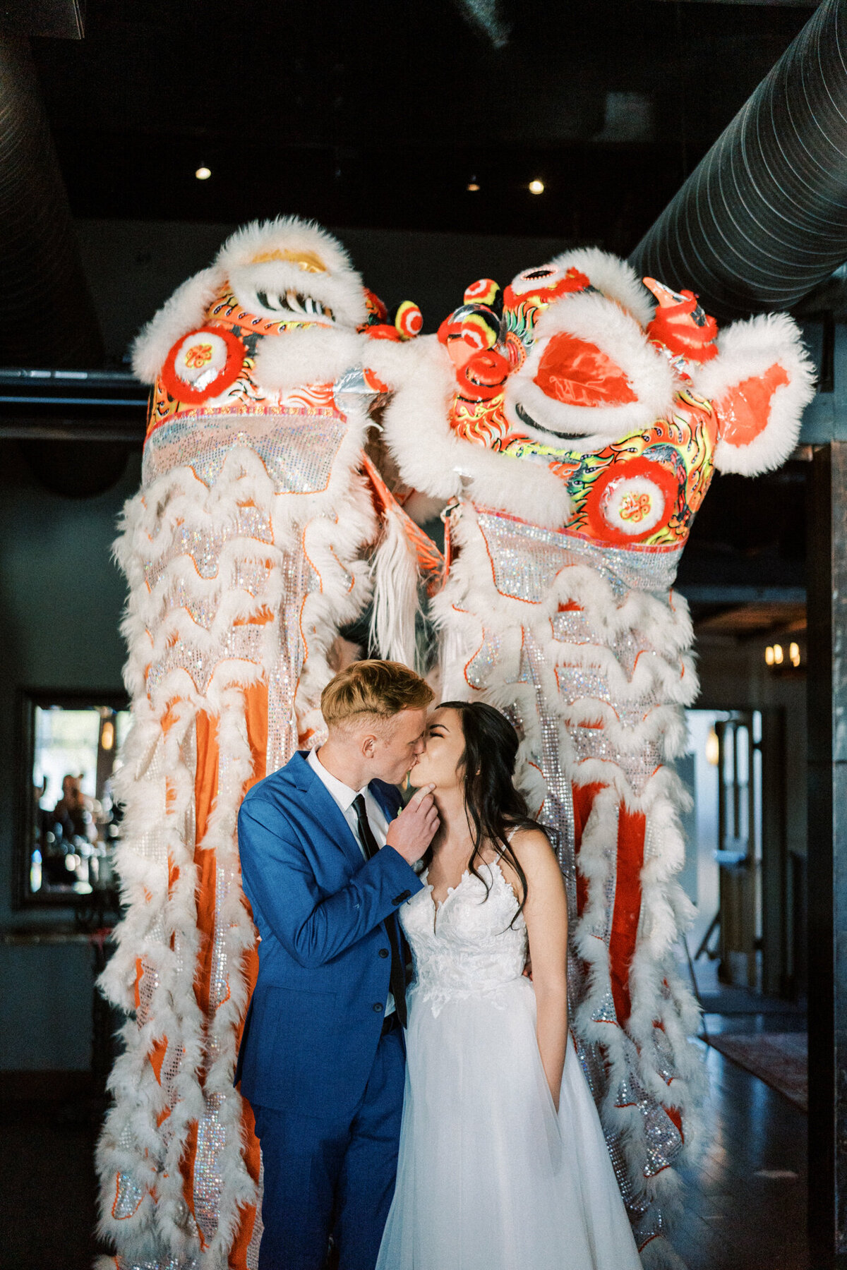 Bride and groom kissing in front of Chinese dragons captured by Pam Kriangkum Photography, fine art, classic wedding photographer in Edmonton, Alberta. Featured on the Bronte Bride Vendor Guide.