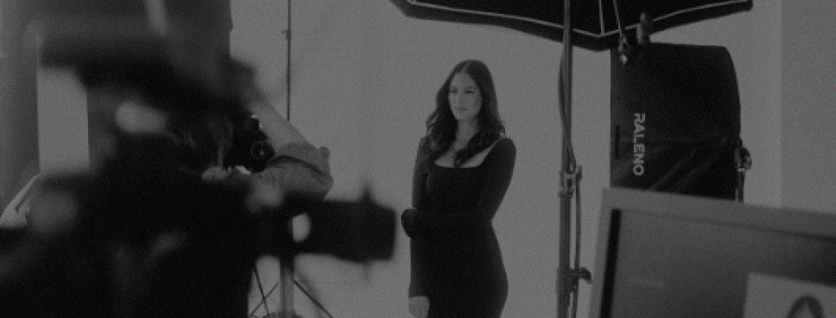 A female model on set with cameras capturing her poses.
