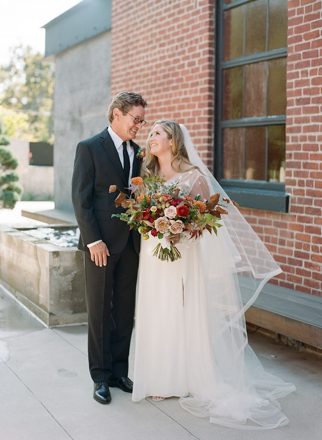 A whimsical bridal bouquet filled with burgundy, terra cotta, dusty rose and burnt orange florals. The bouquet features ranunculus, garden roses, dahlias, fruiting branches and autumn foliage. Designed by Rosemary and Finch in Nashville, TN.