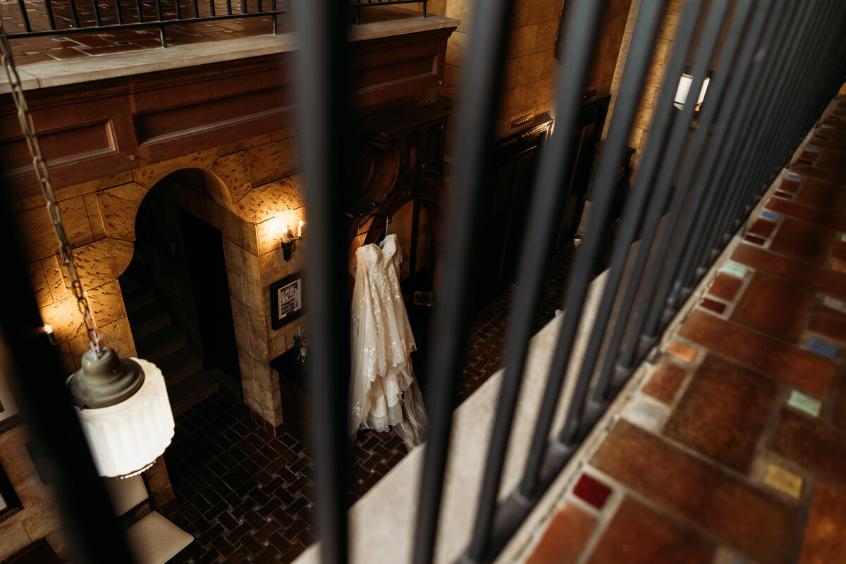 Overhead view from balcony of wedding dress hanging in grand entryway at historic Treasury on the Plaza in St. Augustine.
