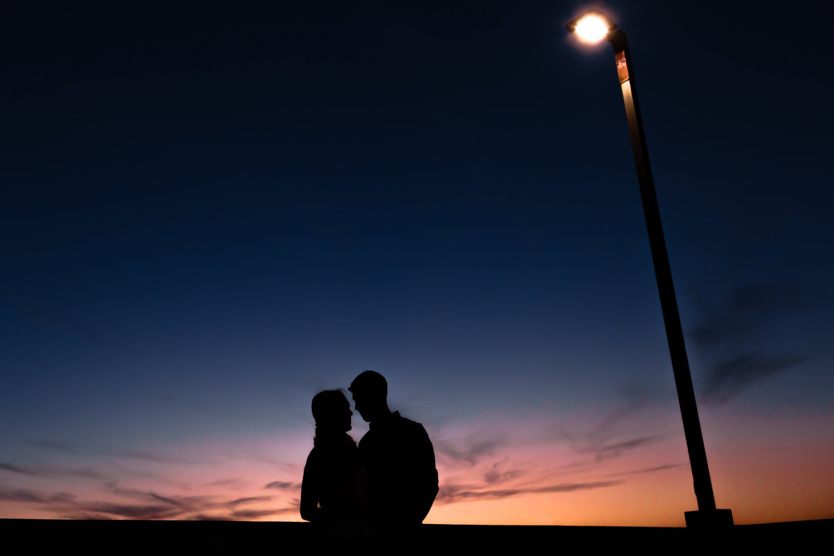 The couple kisses in front of a sunset in Portsmouth NH