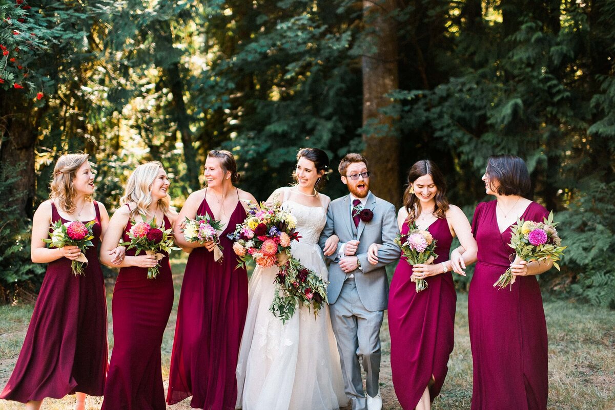 Bride and Bridesmaids and bridesman laughing in the forest at a vashon island wedding