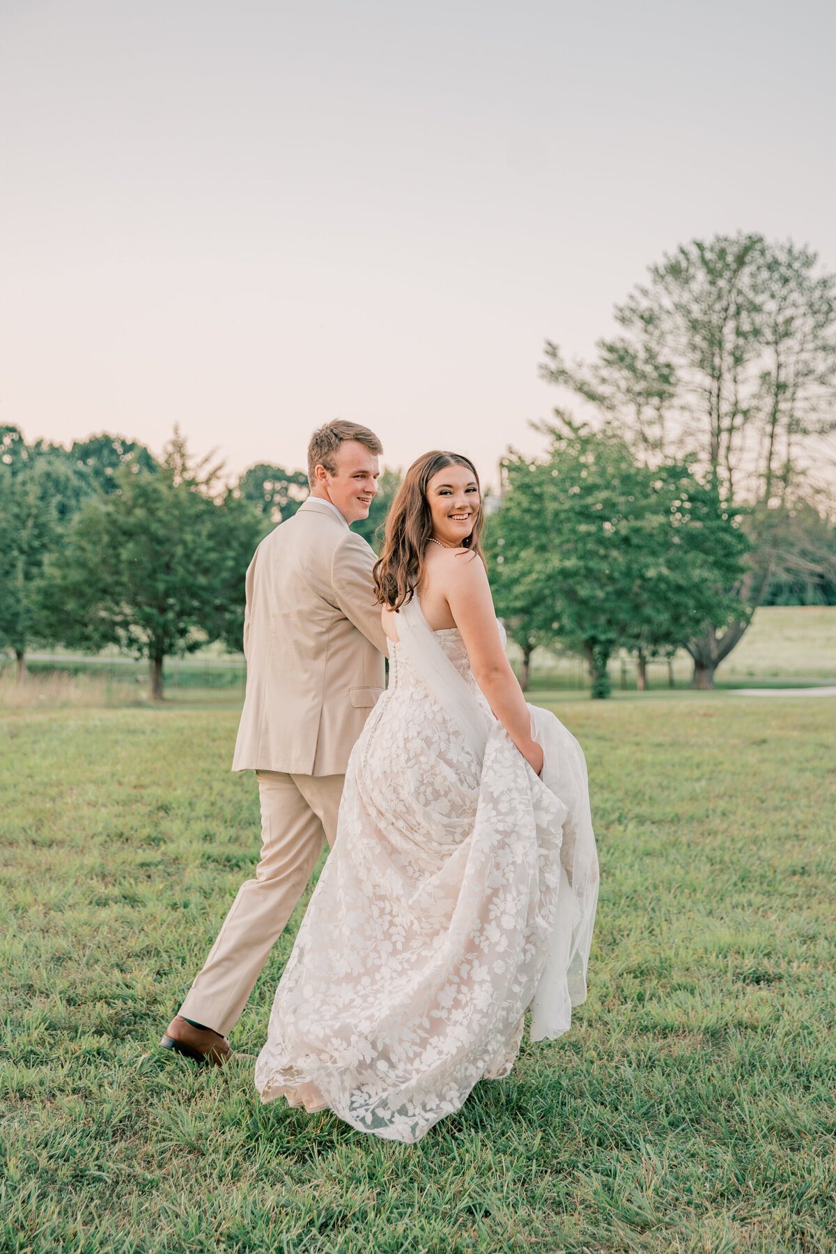 Three Oaks Manor Wedding | bride and groom walk hand in hand at sunset
