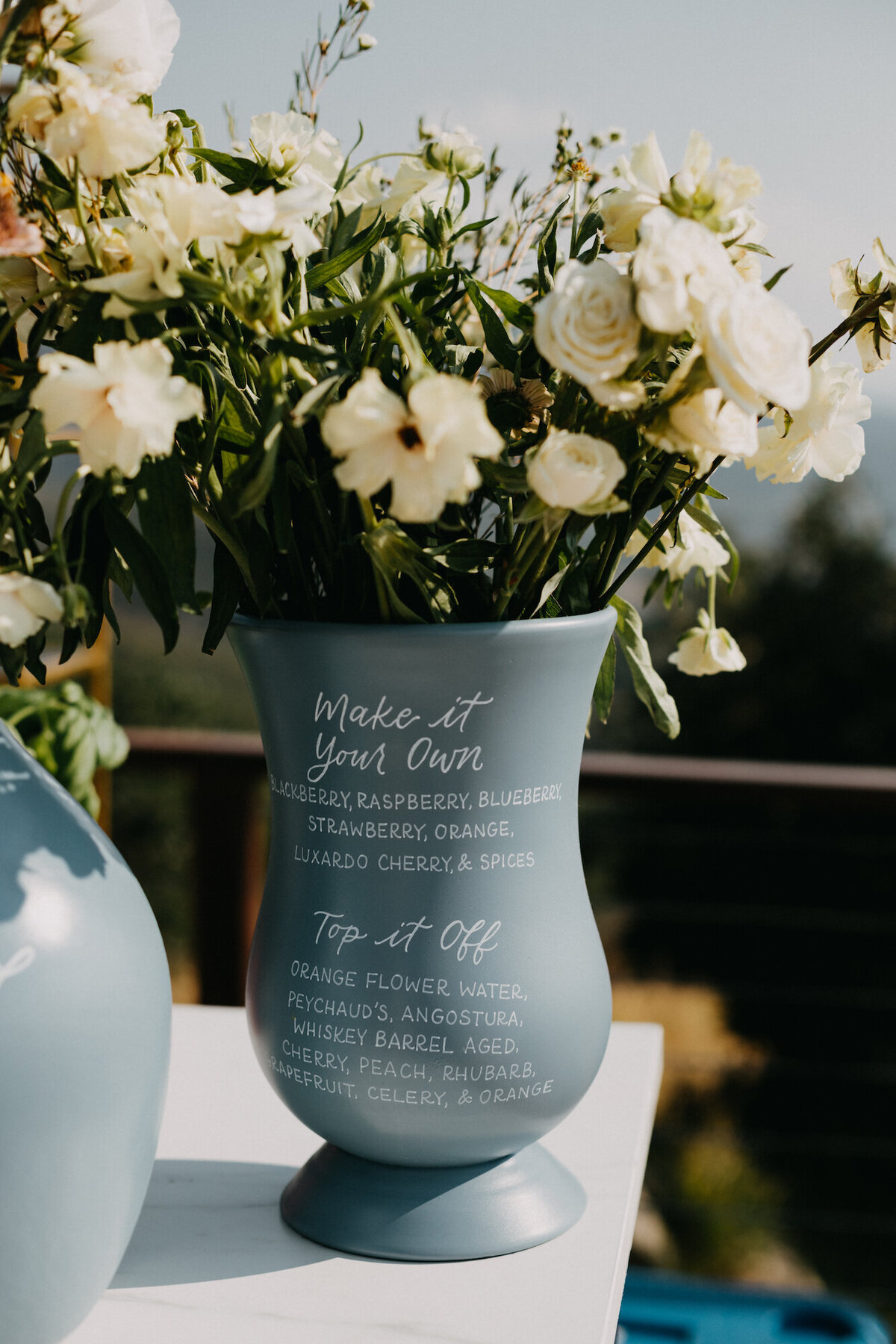 Dusty blue bar sign on a jug, filled with florals