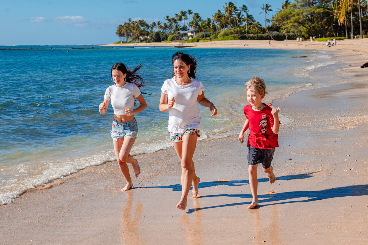 Sonia running with her kids on a beach in Oahu