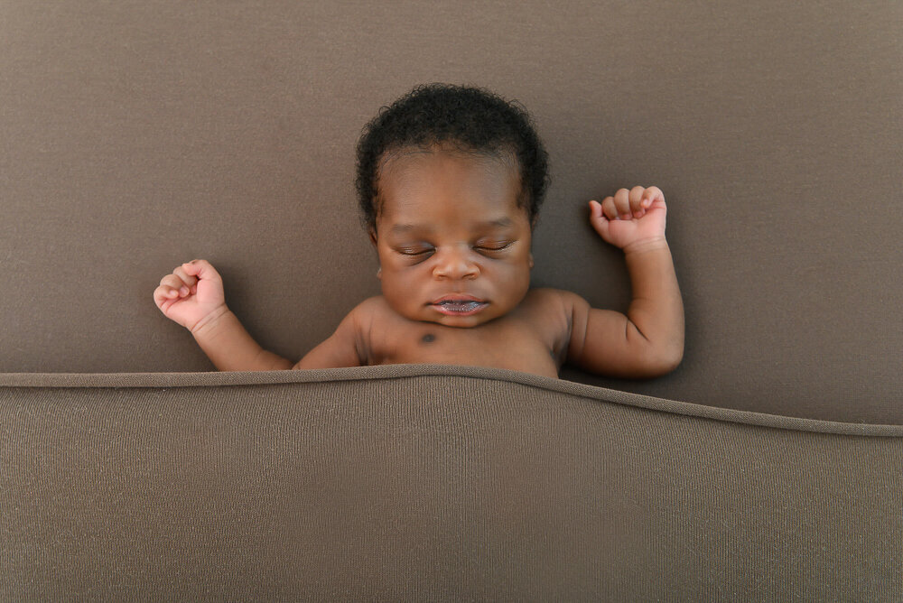 black newborn baby boy on a brown background in Hamilton, Ontario.