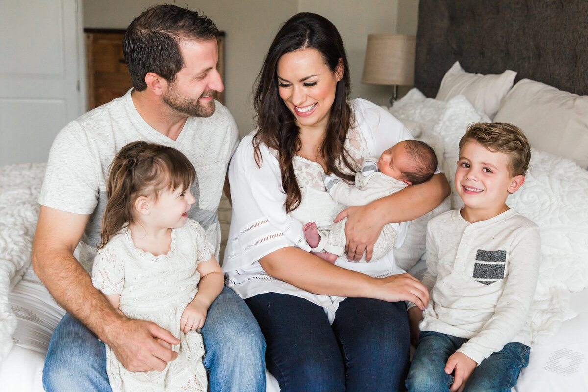 family smiling together with newborn baby