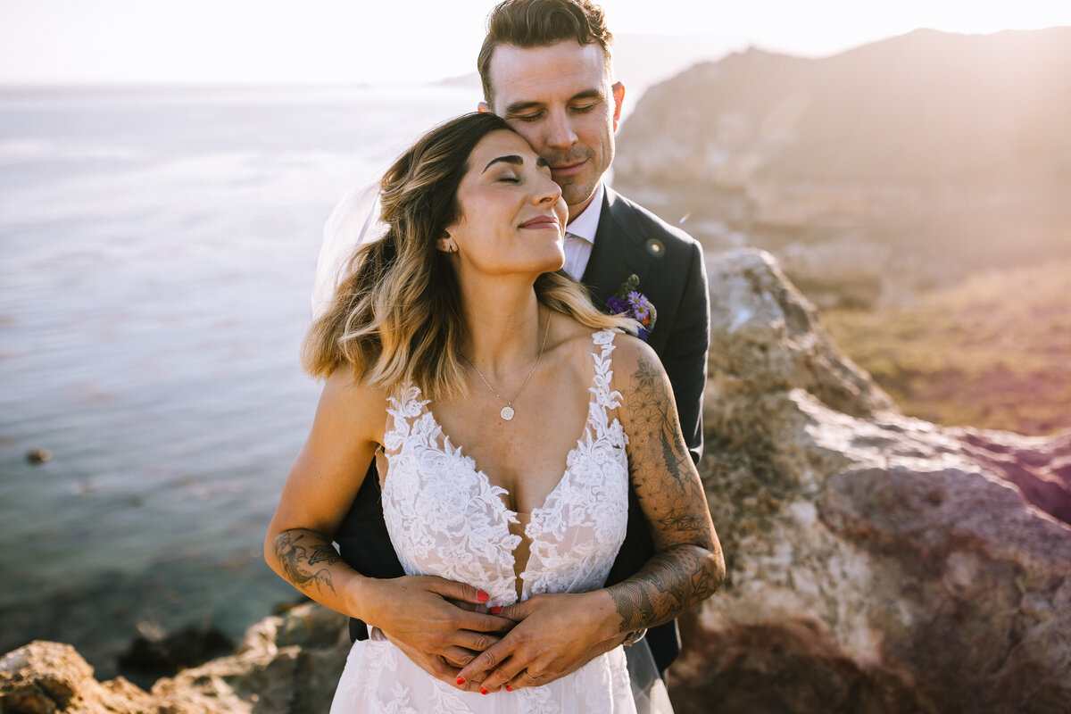 Bride and groom on a cliff over the water in San Luis Obispo. 