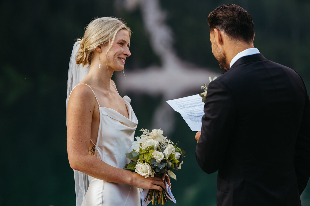 Bride smiling as groom reads vows at Dolomites elopement