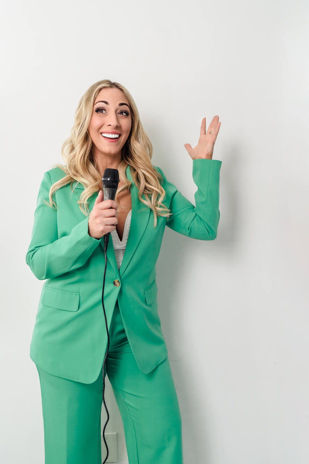 Female speaker in green suit gesturing with her hand while delivering a speech.