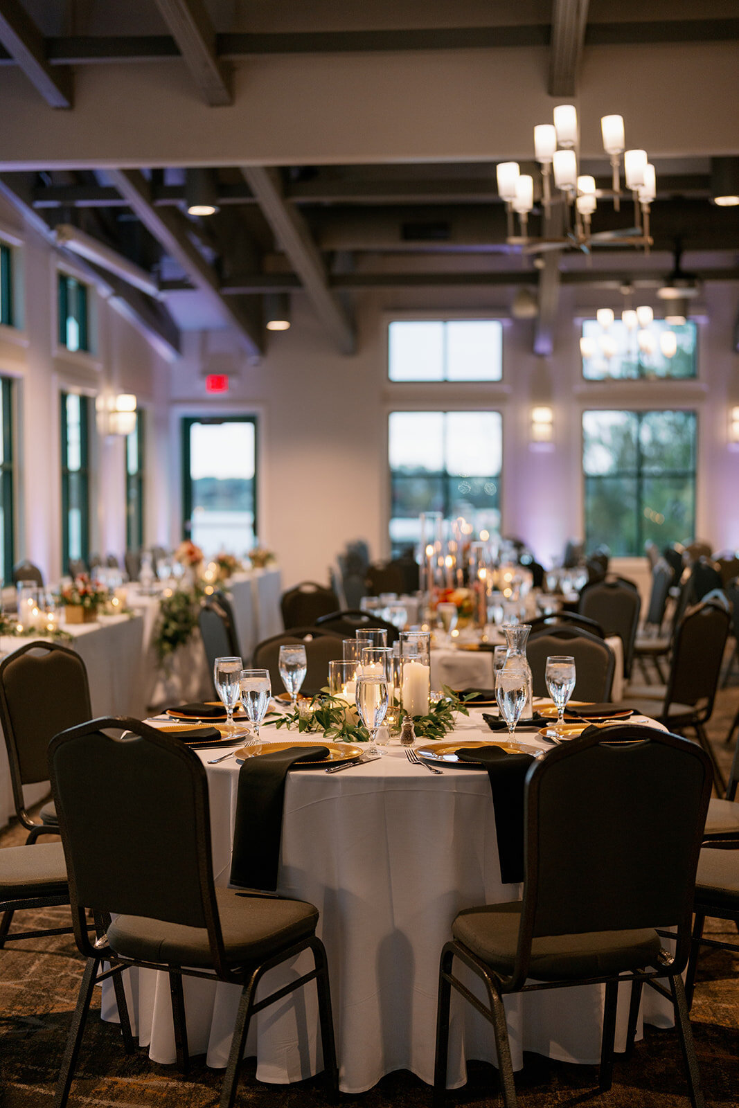 Elegant wedding reception setup at Boatwerks Waterfront Venue in Holland Michigan with candles, florals, and round tables.