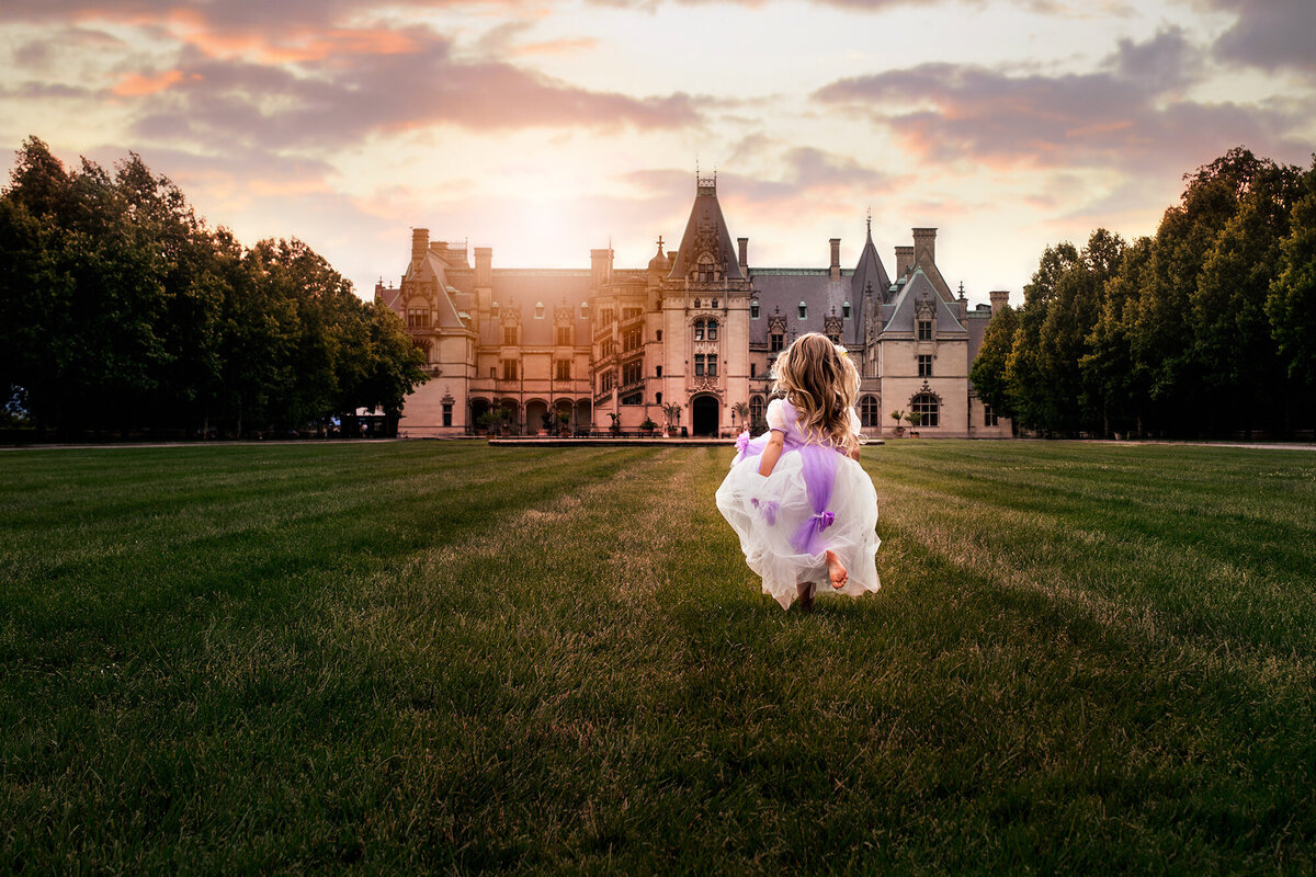 A little girl in a princess dress running on the lawn in front of the Biltmore Estate in Asheville NC
