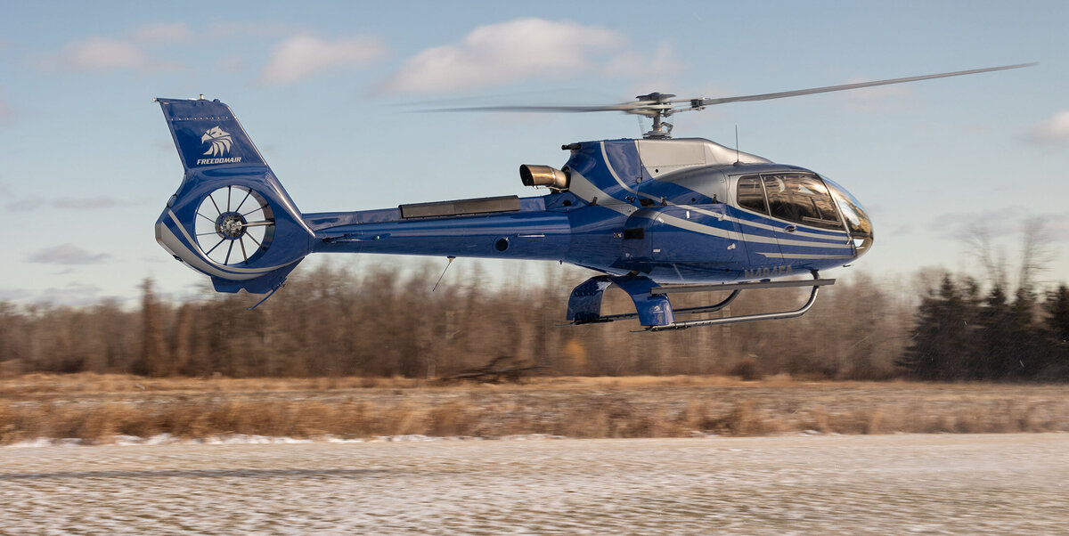 blue airbus ec130 b4 helicopter flying in sky - on-demand helicopter services