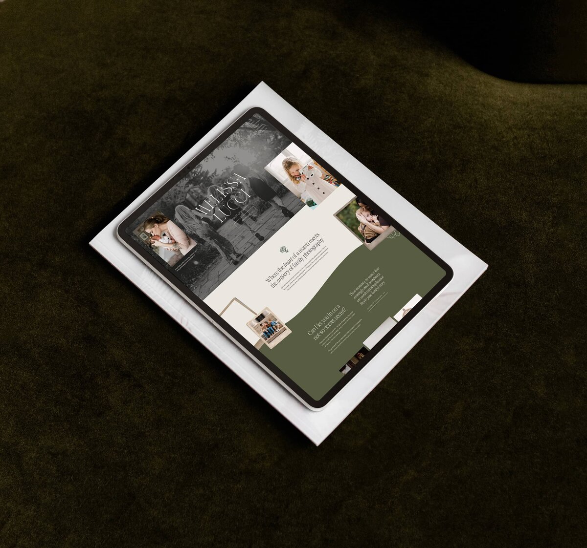 A tablet showcasing a wedding-themed photography website designer's portfolio rests on a stack of white envelopes against a dark green background. The site features a header image of a happy couple and various wedding-related sections.