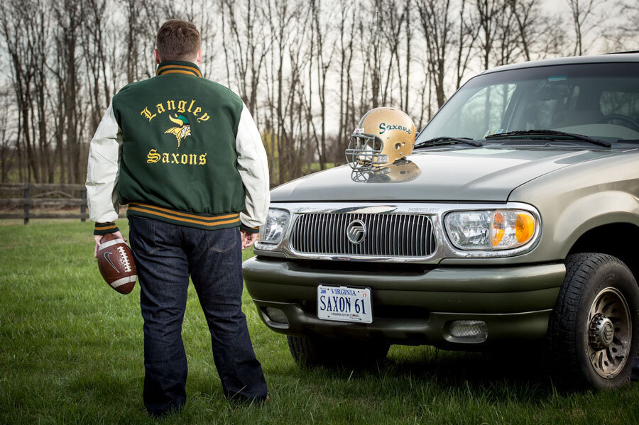 senior boy in field with car and football