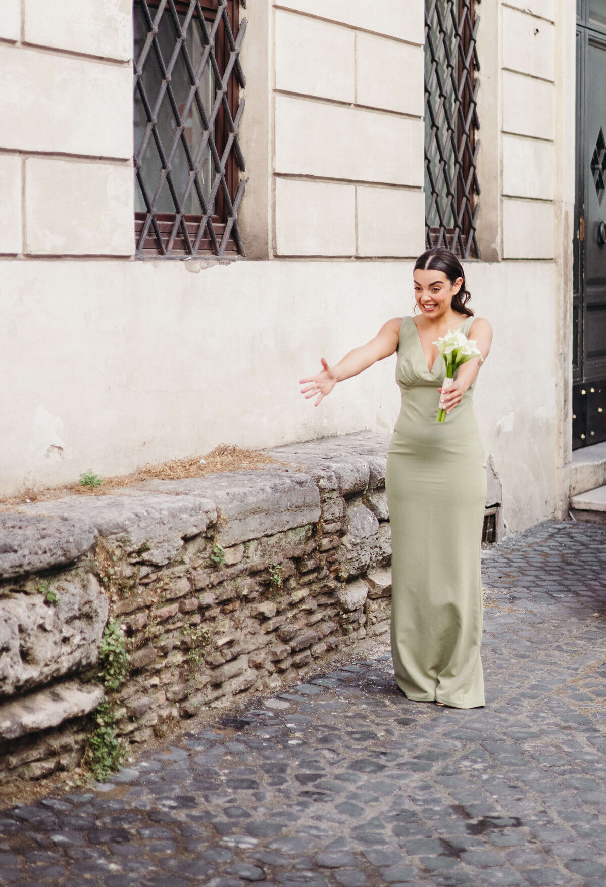 Bridesmaid in green satin dress posing in Roman alley before ceremony
