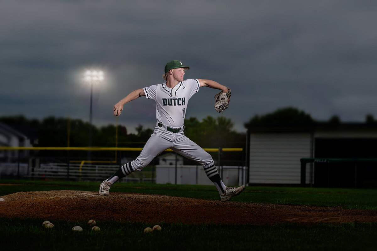 A moment captured by a Pella Senior Photographer of a baseball pitcher mid pitch on the mound in the evening in his Pella high school jersey