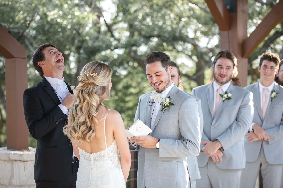 groom smiles while reading his vows and pastor laughs at Milestone Georgetown wedding