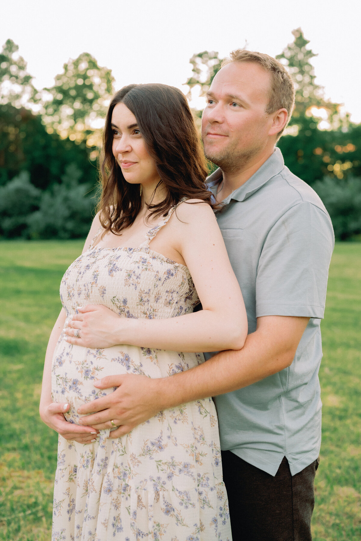 Mother and father staring forward while holding baby bump