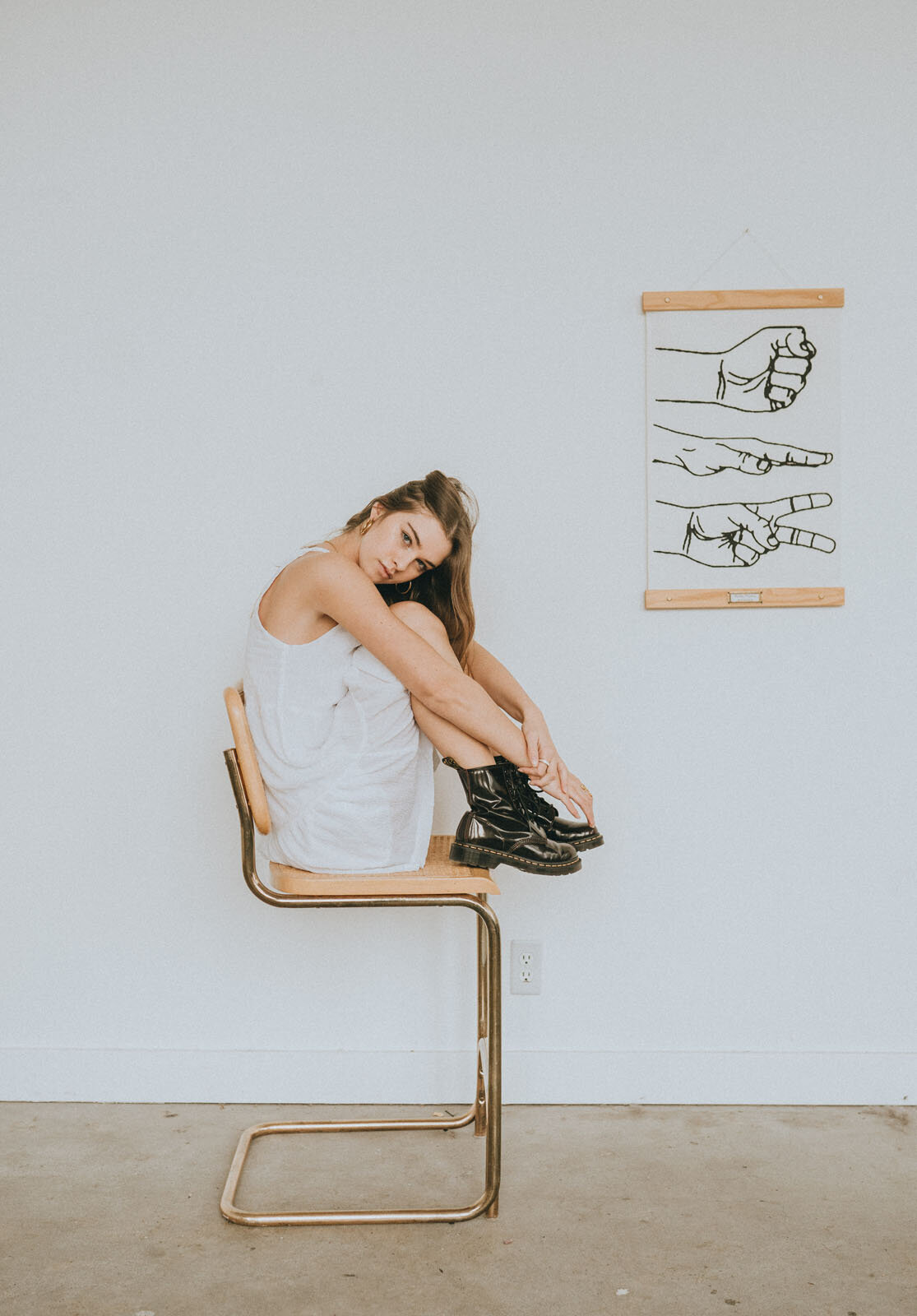 Girl sitting on chair with feet tucked in towards her