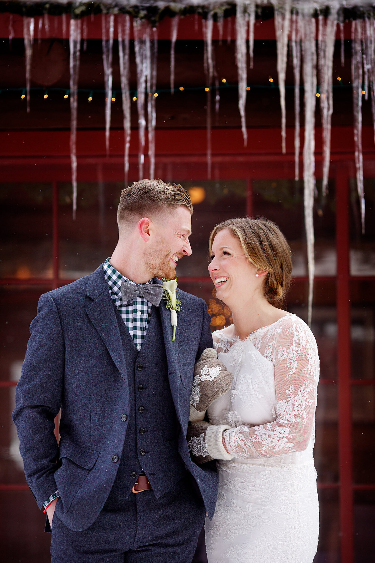 A bride and groom laugh as they snuggle to keep warm before their winter wedding ceremony at Elkins Resort on Priest Lake near Nordman, Idaho.