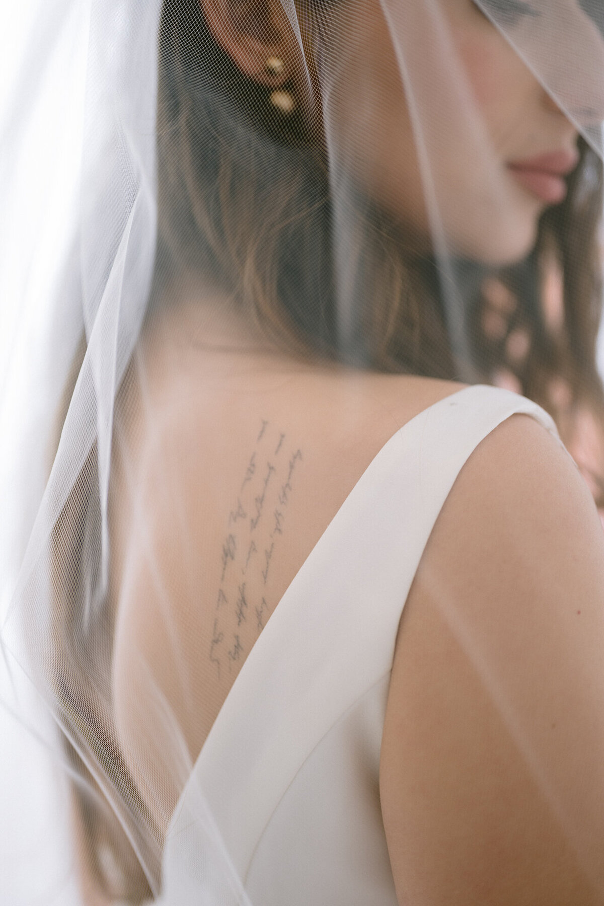 Bride in her veil and revealing her tattoo on her back