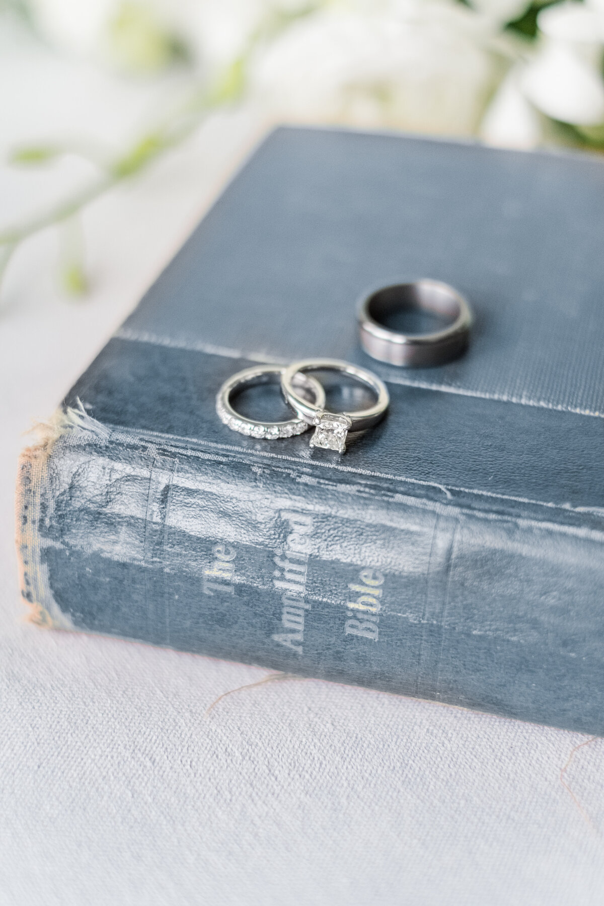 wedding rings sitting atop blue bible