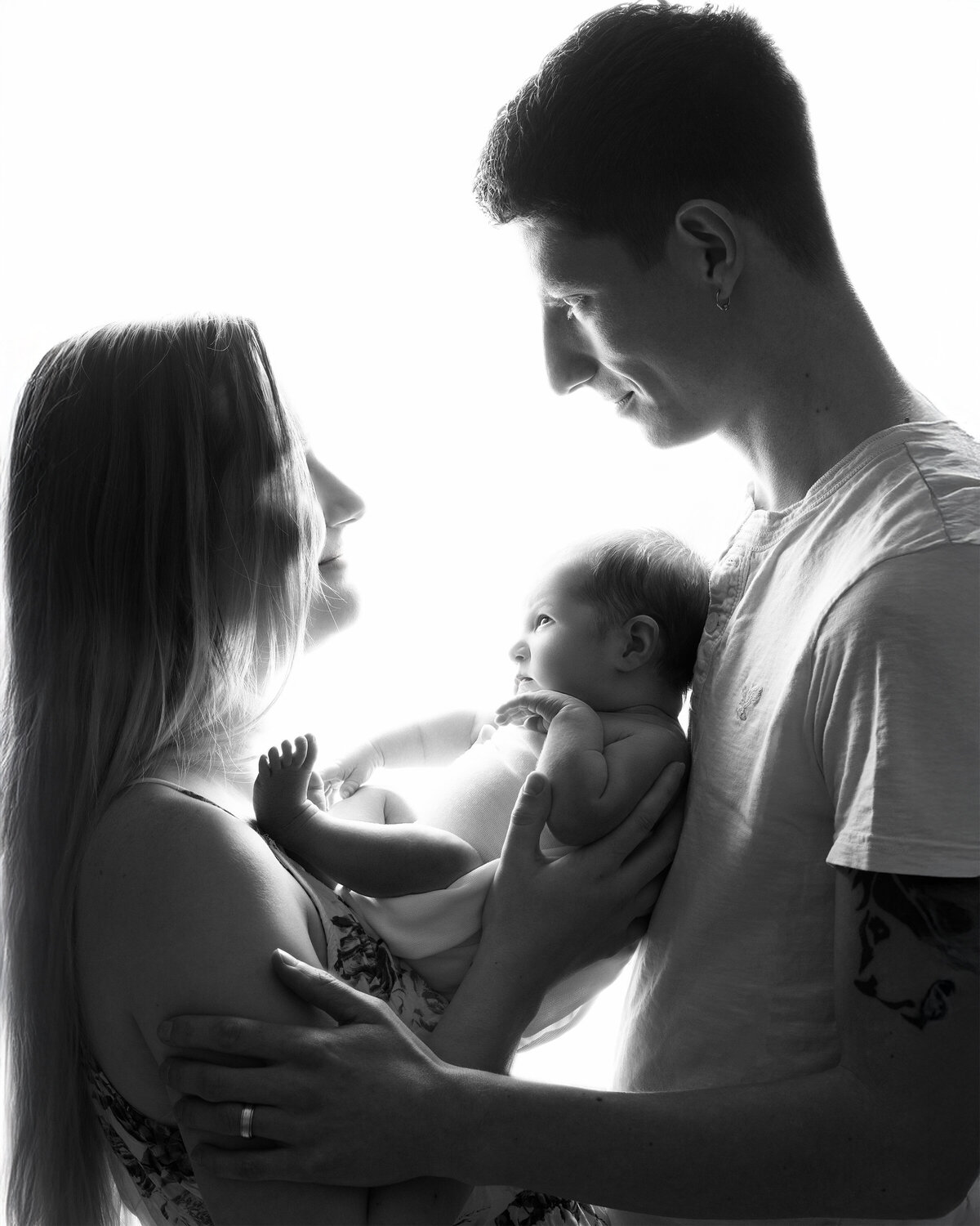 Studio backlit portrait of parents admiring their newborn baby | Family photography Paris Ontario
