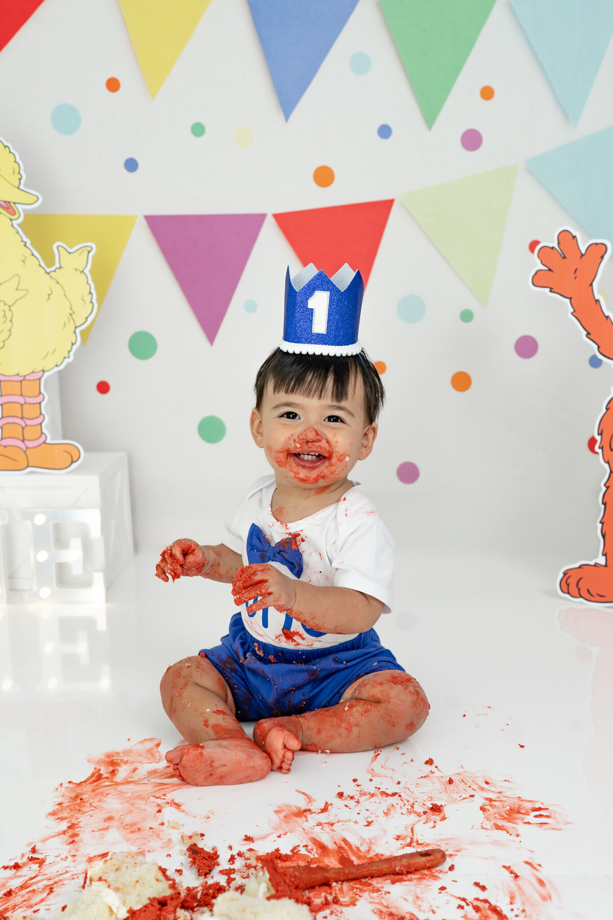 Boy in birthday outfit eating an Elmo cake during themed cake smash session— captured by Alliston and Barrie cake smash photographer.