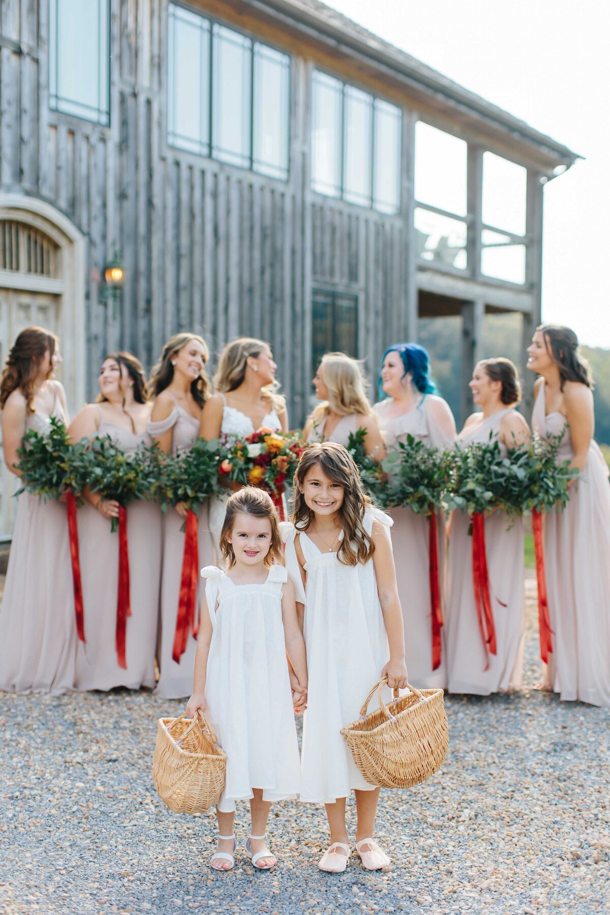 Flower girls look at camera with bridesmaids in background at crooked river wedding venue