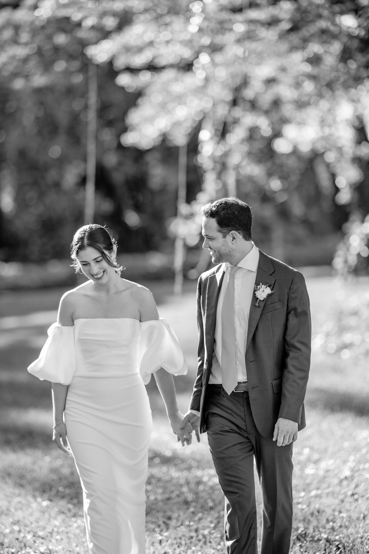 Bride and groom holding hands and walking, captured in a timeless black and white moment.