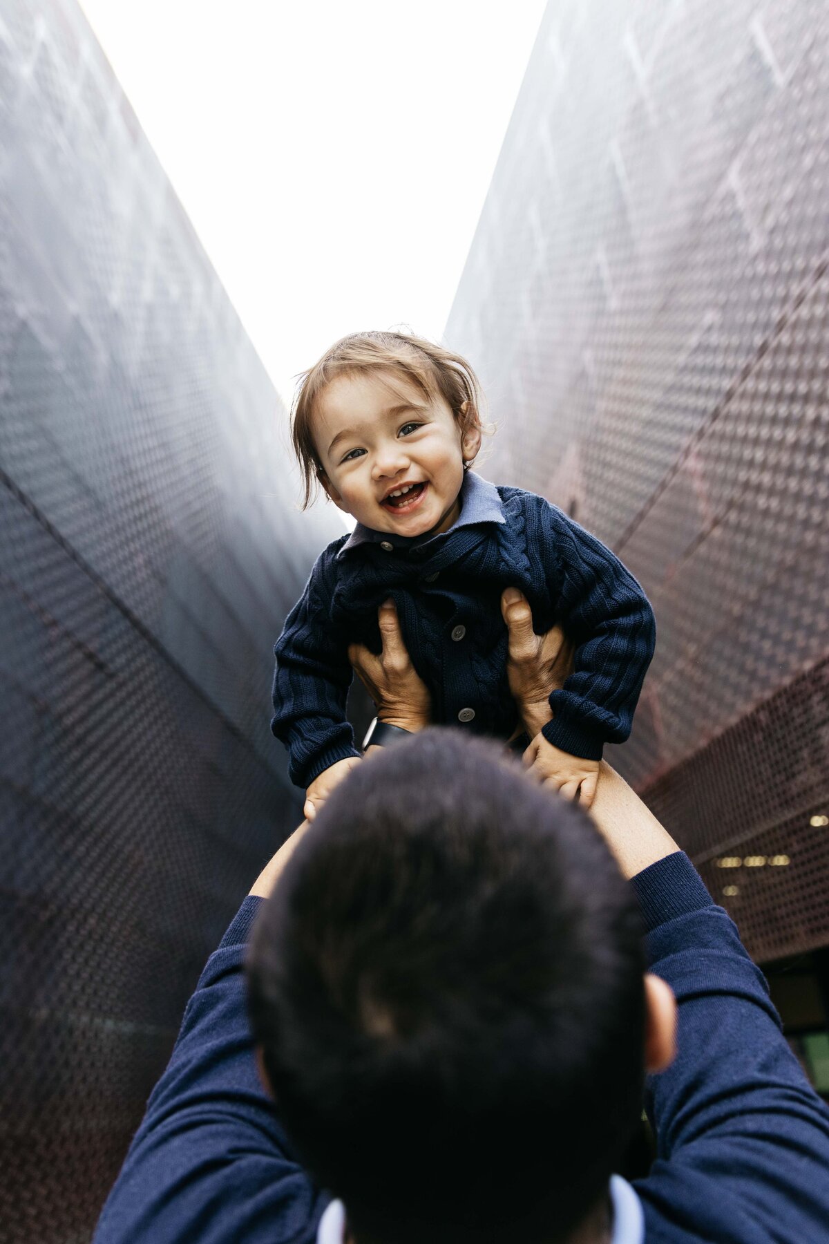 Dad is tossing toddler son high in the air at the DeYoung Museum.