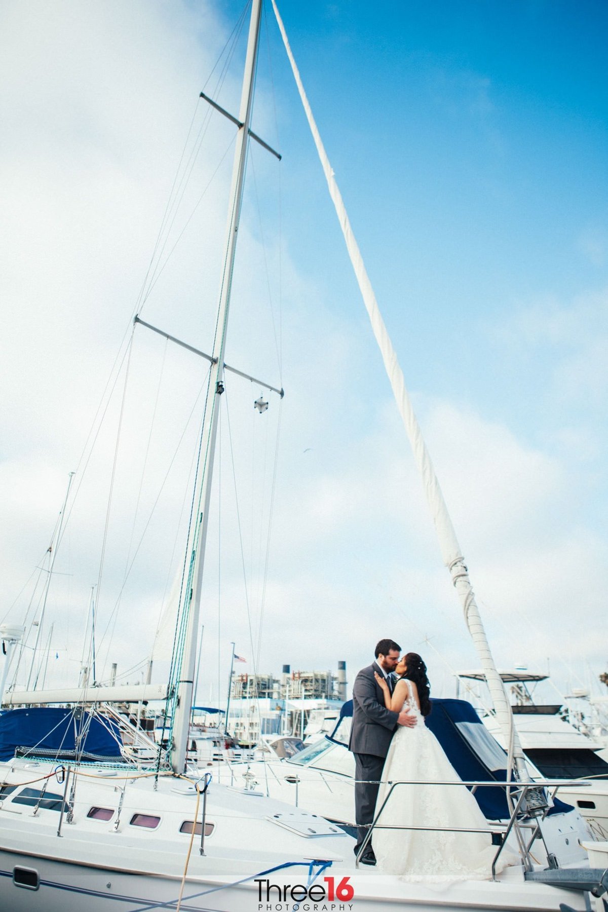 Bride and Groom share a kiss while standing on the back of a sailboat