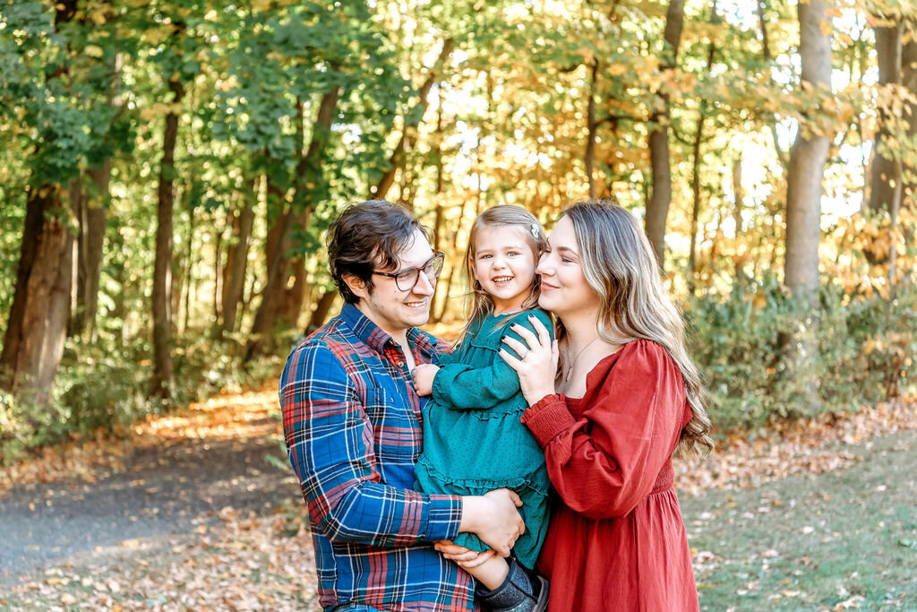 Connecticut family photographer captures loving family of three in coordinating fall colors during golden hour outdoor session