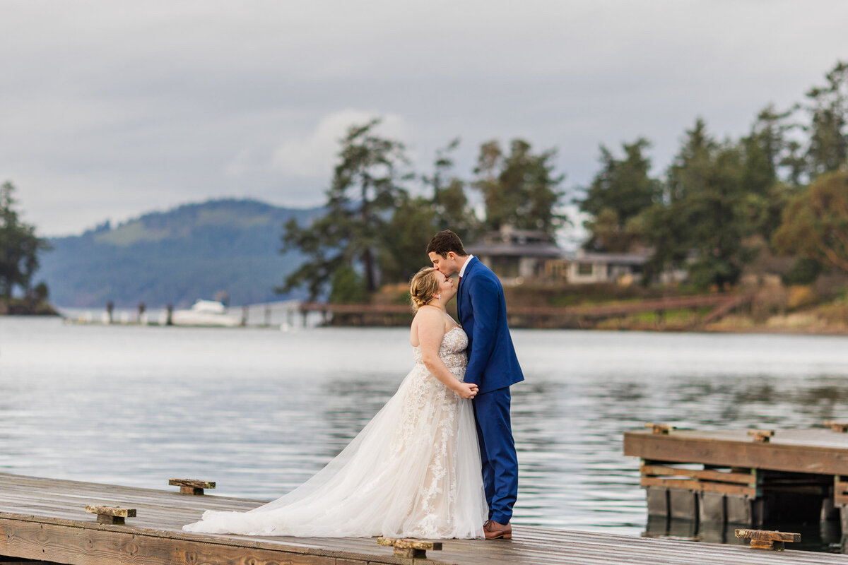 Roche-Harbor-wedding-venue-with-Puget-Sound-and-mountain-views-couple-kiss-on-dock-at-San-Juan-Island-photo-by-Joanna-Monger-Photography