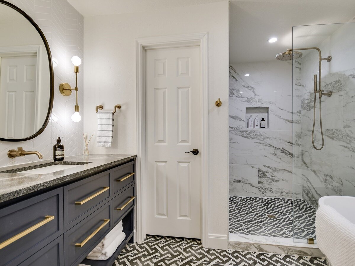 Main bathroom with decorative tile, shower and large black mirror
