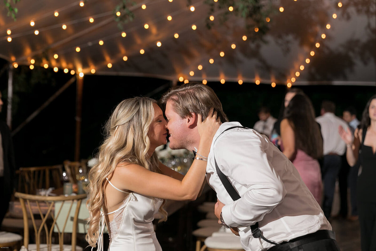 Bride and groom kissing under market lights at Long Island wedding reception