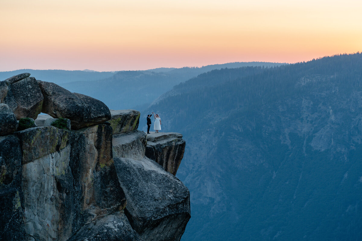 Bride and Groom eloping at Yosemite National Park Taft Point cliff during sunset dancing on cliff.
