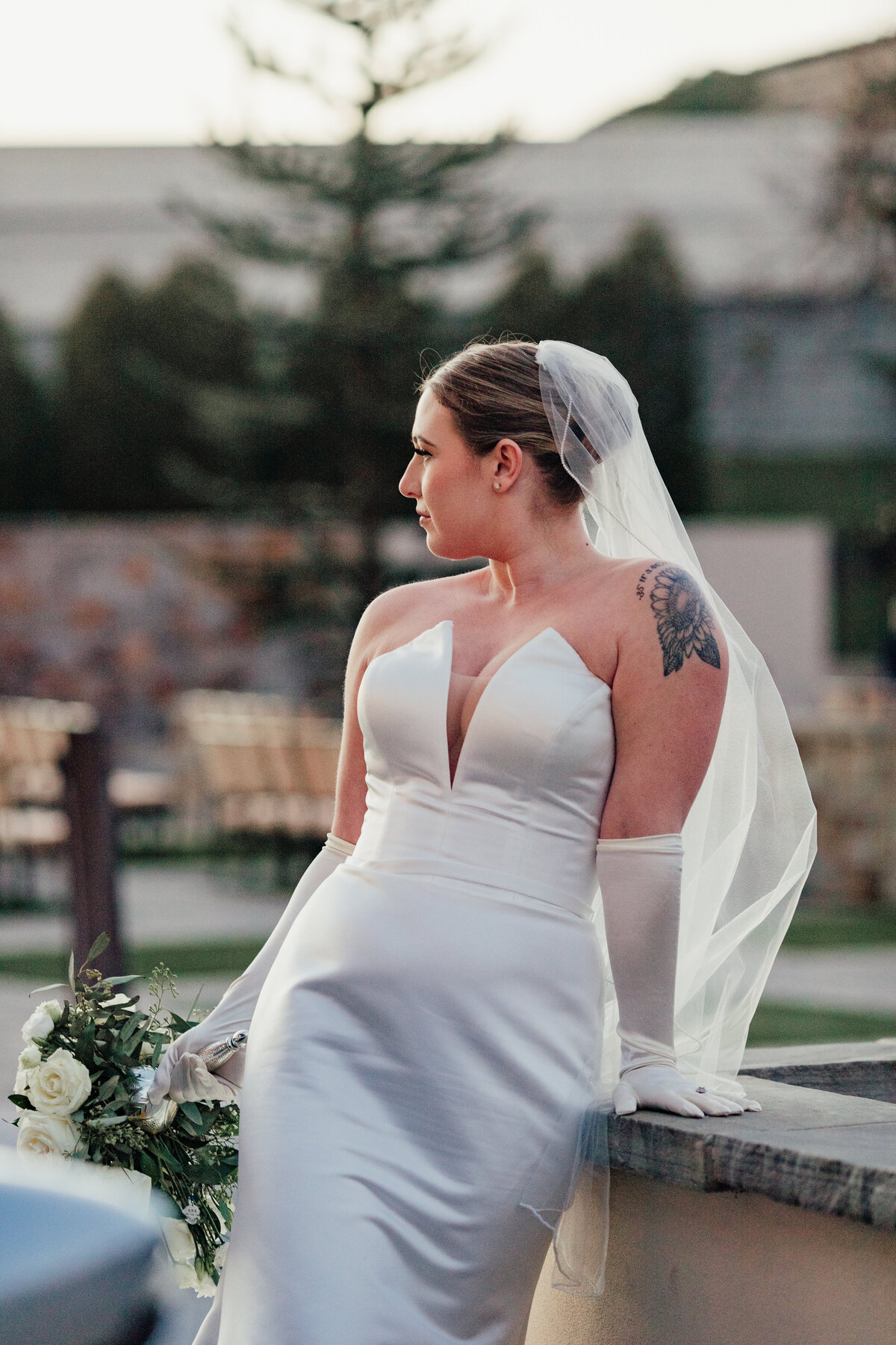 bride leans onto a fountain holding her flowers