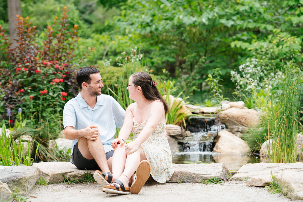 Candid engagement portraits at Acton Arboretum in Massachusetts with greenery and emotion.